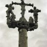 Détail du calvaire de Lampaul-Guimiliau. Plus simple que la plupart des calvaires présents dans les enclos paroissiaux, il est constitué d'un fût écoté érigé sur un socle octogonal (le nombre 8 symbolise l'éternité). A son sommet, un Christ en croix entouré des deux larrons et (au pied de la croix) deux anges qui présentent le Graal pour y recueillir le sang du Christ.   